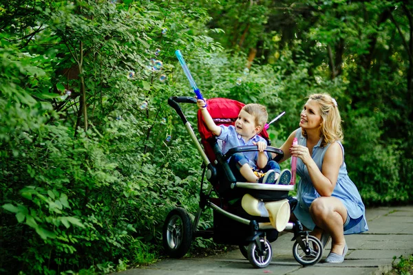 Mujer soplando burbujas de jabón con niño — Foto de Stock