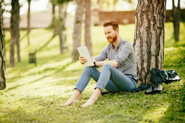Parkta tablet kullanan bir işadamı