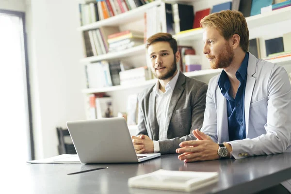 Jeunes hommes d'affaires assis au bureau — Photo