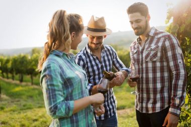 İnsanlar üzüm bağında şarap tadıyor.