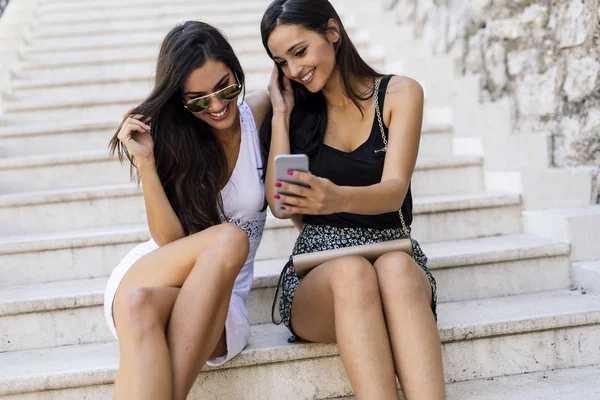 Women holding phone and smiling — Stock Photo, Image