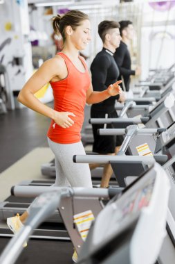  bir spor salonunda koşu bandı kullanan kişiler