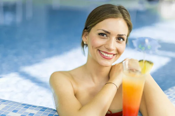 Mujer en una piscina con un cóctel — Foto de Stock