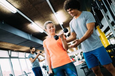 Genç ve güzel bir kadın spor salonunda antrenörle egzersiz yapıyor.