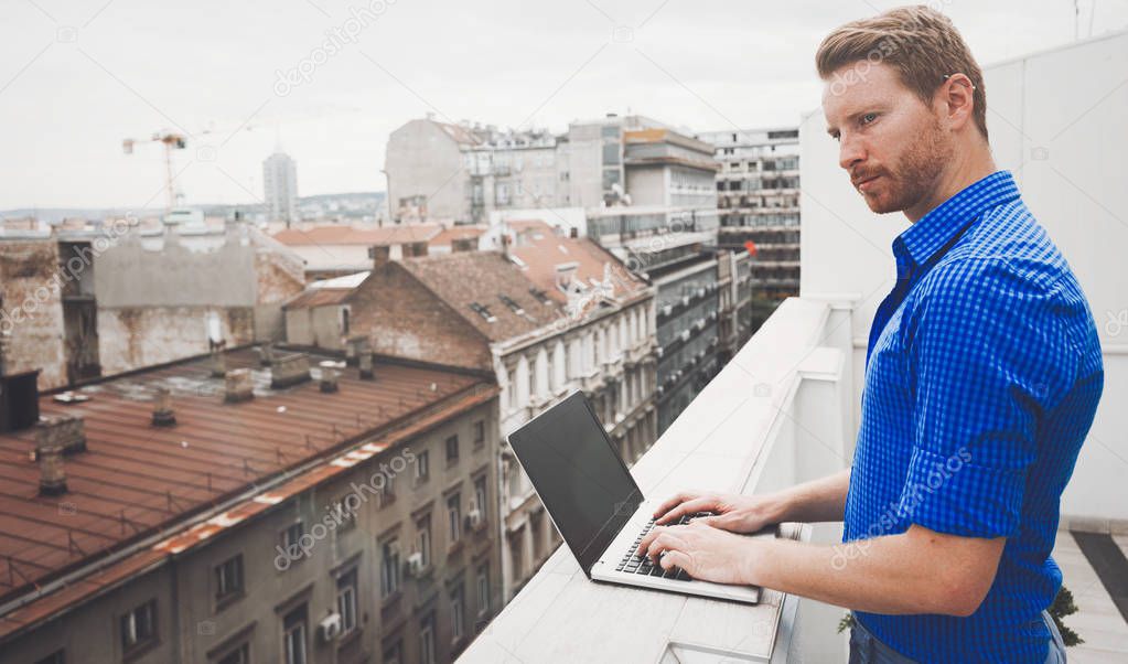Business person using laptop on rooftop