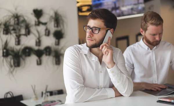 Pensive young businessman in cafe using phone — Stock Photo, Image