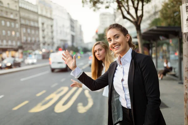 Mulheres de negócios acenando para táxi — Fotografia de Stock