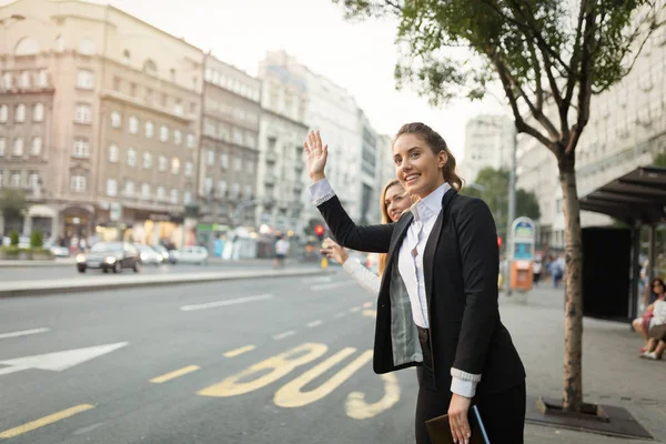 Mulheres de negócios acenando para táxi — Fotografia de Stock