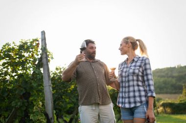 İnsanlar üzüm bağında şarap tadıyor.