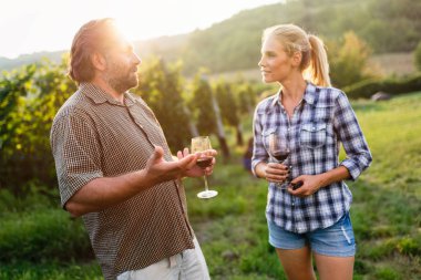 İnsanlar üzüm bağında şarap tadıyor.