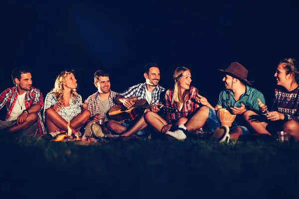 Amigos disfrutando de música cerca de fogata — Foto de Stock