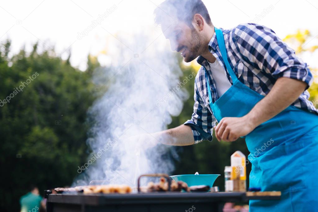 Handsome happy male preparing barbecue 