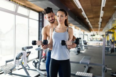 Genç kadının pazı eğitmen ile spor salonunda egzersiz yapması