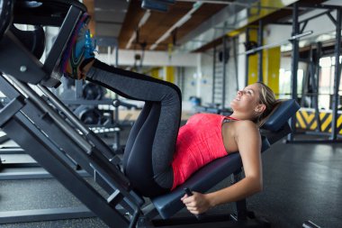 Kadının bacak basın makine üzerinde spor salonunda egzersiz yapması