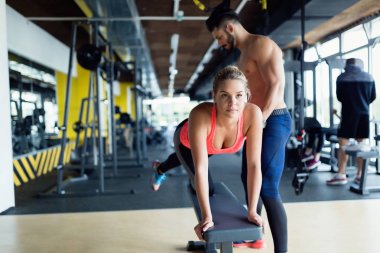 Genç güzel kadın çalışma egzersizleri ile spor salonunda antrenör