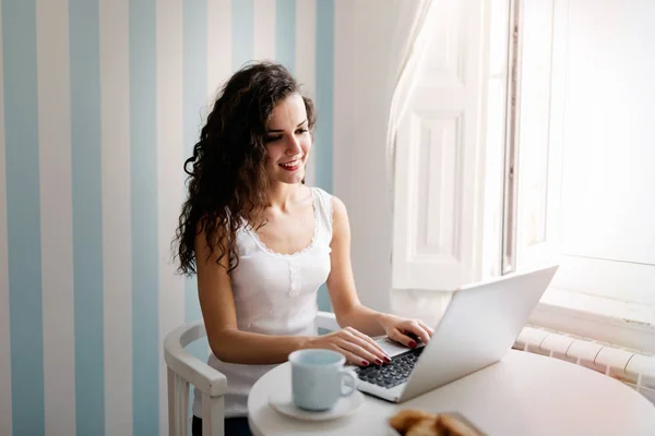 Kvinnan ler och använder bärbar dator — Stockfoto