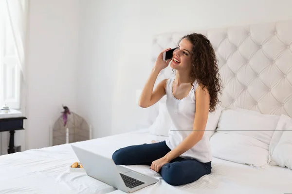 Ung kvinna med telefon och laptop — Stockfoto