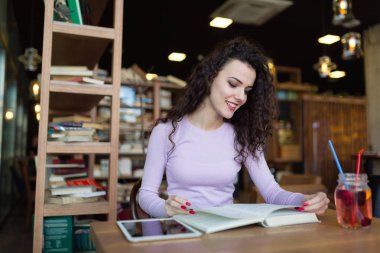 Genç kadın kahve dükkanında kitap okumak