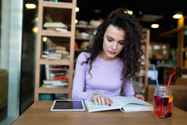 Genç kadın kahve dükkanında kitap okumak