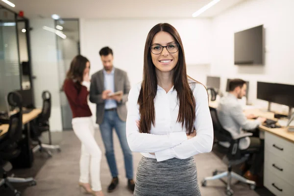 Empresária posando enquanto outros empresários conversam — Fotografia de Stock