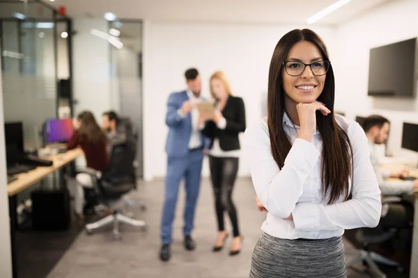 Бізнес-леді позує в той час як інші бізнесмени говорять — стокове фото