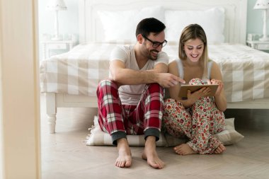 Yatak odasında tablet kullanan çift