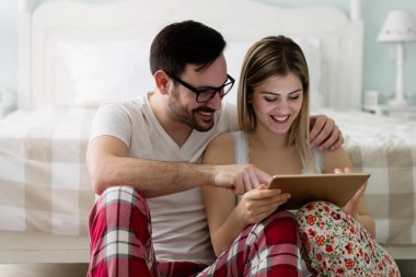 Yatak odasında tablet kullanan çift