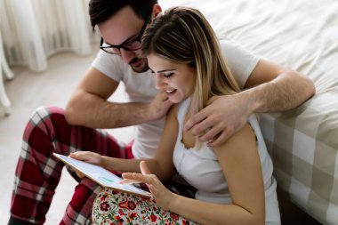 Yatak odasında tablet kullanan çift