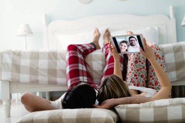 Yatak odasında tablet kullanan çift