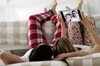 Yatak odasında tablet kullanan çift