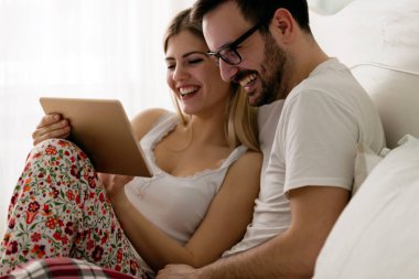 Yatak odasında tablet kullanan çift