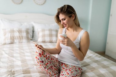  yatakta dijital tablet kullanan kadın