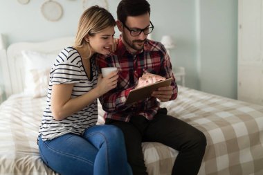 Yatak odasında tablet kullanan çift