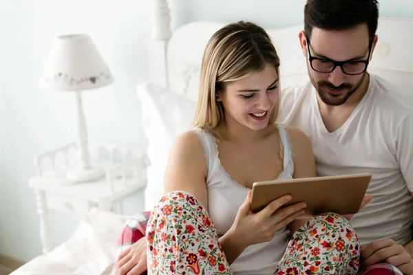 Pár pomocí tablet v ložnici — Stock fotografie