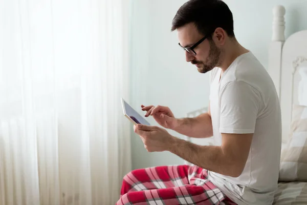 Ο άνθρωπος που χρησιμοποιώντας ψηφιακό tablet στο κρεβάτι — Φωτογραφία Αρχείου