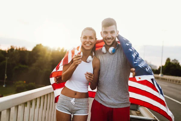 Fitness couple holding American flag — Stock Photo, Image