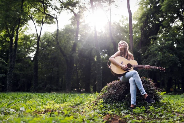 Schöne Frau spielt Gitarre in der Natur — Stockfoto