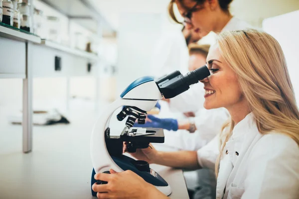Joven científico mirando a través del microscopio — Foto de Stock