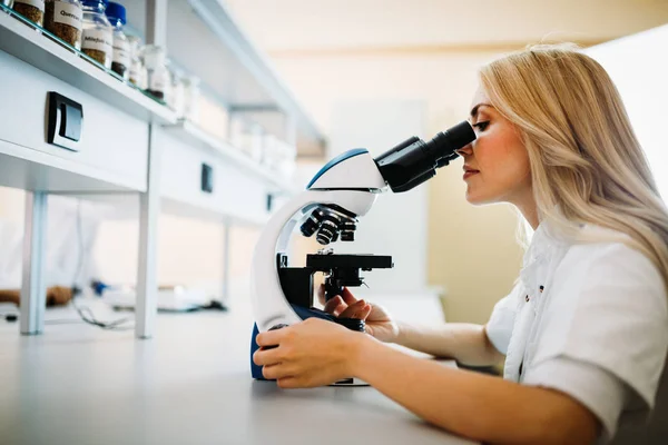 Jovem cientista olhando através do microscópio — Fotografia de Stock