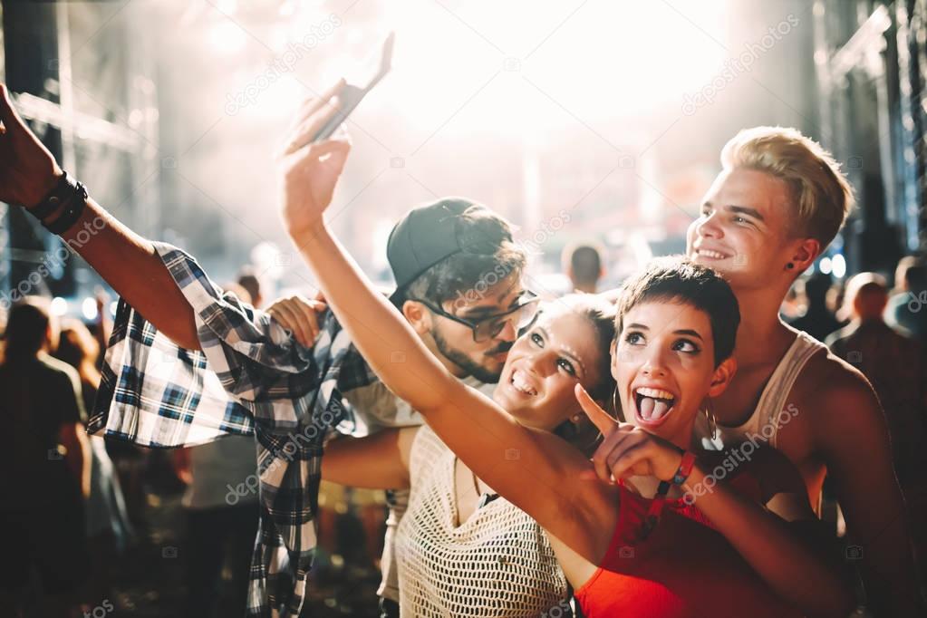Happy young friends taking selfie at music festival