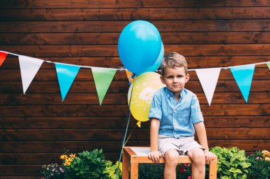 Doğum günü partisinde masada oturan genç güzel çocuk portresi