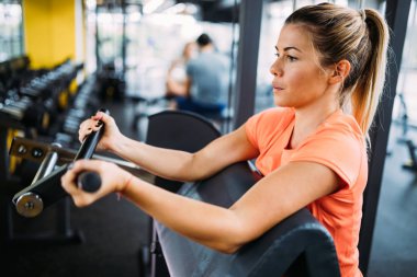 Genç güzel kadın için spor salonunda pazı egzersizleri yapıyor