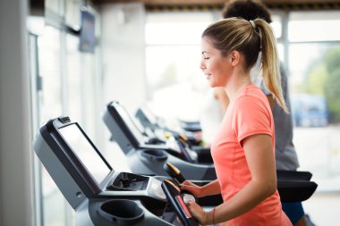 Genç çekici kadın spor salonunda ağırlık kaybı için kardiyo egzersizi yapıyor