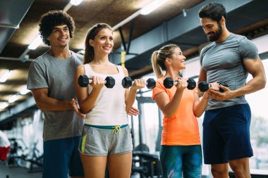 Genç güzel kadın spor salonunda kişisel eğitmenler ile yapıyor