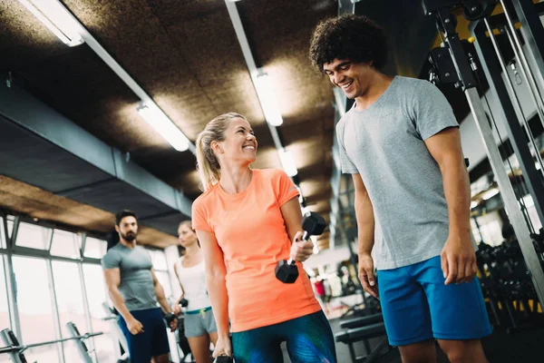 Genç ve güzel bir kadın spor salonunda antrenörle egzersiz yapıyor.