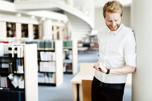 Student checking time in library — Stock Photo, Image