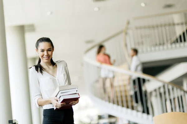 Hermosa Mujer Sosteniendo Libros Sonriendo Una Biblioteca Moderna — Foto de Stock