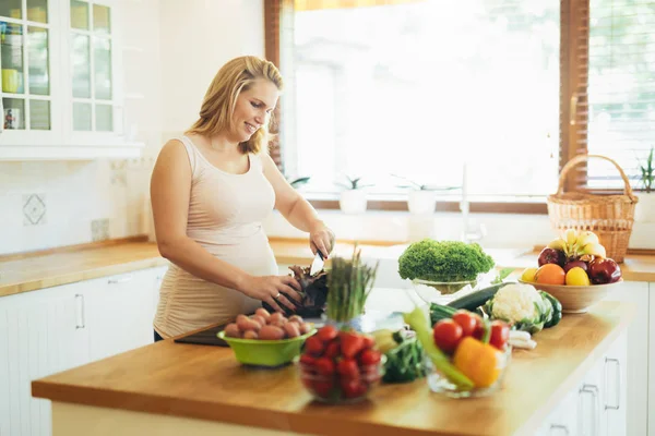 Красива вагітна жінка готує їжу — стокове фото