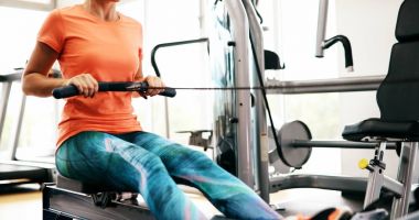 Spor salonunda kürek makine üzerinde çalışan genç sarışın kadın