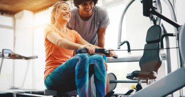 Genç ve güzel bir kadın spor salonunda antrenörle egzersiz yapıyor.